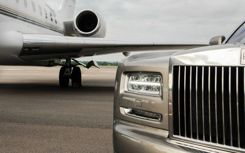 Close-up of a luxury car and a private jet on the runway.